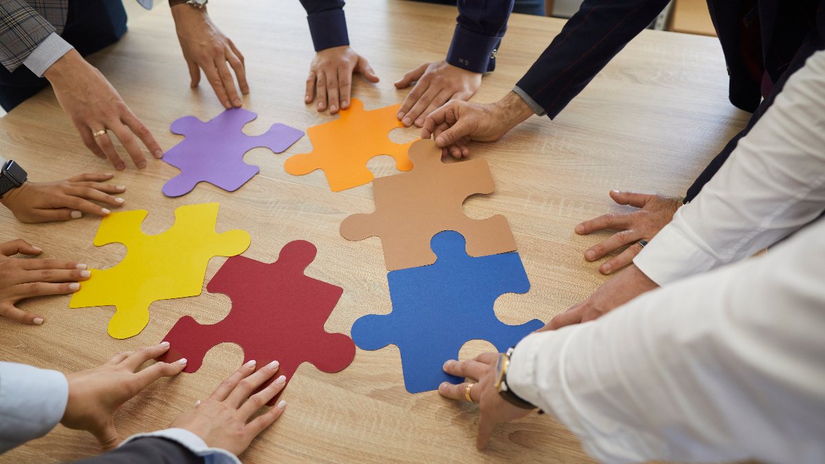 A team fitting colorful puzzle pieces together on a table